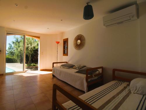 a bedroom with two beds and a sliding glass door at Villa Tara 6 chambres piscine privée vue panoramique sur les collines de Grimaud in Grimaud