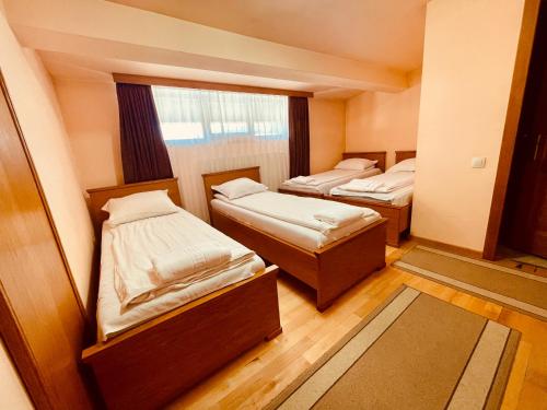 two beds in a small room with a window at Rákóczi Center in Odorheiu Secuiesc