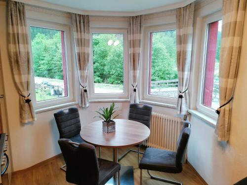 une table et des chaises dans une pièce avec fenêtres dans l'établissement Villa Anna, à Bad Gastein
