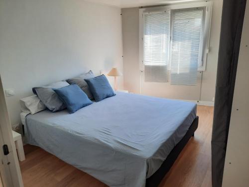 une chambre avec un grand lit avec des oreillers bleus dans l'établissement appartement T3 quartier ARAGO, à Les Sables-dʼOlonne
