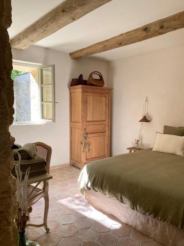 une chambre avec un lit et une armoire en bois dans l'établissement La Maison du Puisatier • Centre historique • Piscine chauffée •Jardin, à Uzès