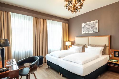 a hotel room with a bed and a desk and a chair at Hotel Würzburger Hof **** in Würzburg