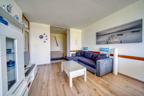 ein Wohnzimmer mit einem blauen Sofa und einem TV in der Unterkunft Ferienpark - Haus F, App 0FEG01 in Heiligenhafen