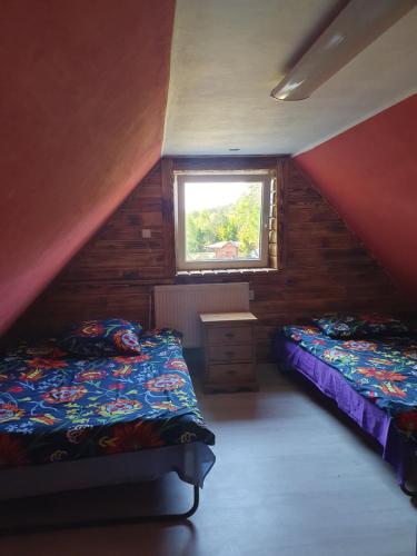 a attic bedroom with two beds and a window at Zielony Domek Papiernia in Lipusz