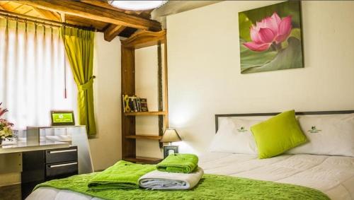 Schlafzimmer mit einem Bett mit grüner Bettwäsche und einem Schreibtisch in der Unterkunft Hosteria Airport Garden in Tababela