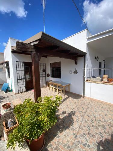 una casa blanca con un porche con un banco en Mandorli in fiore, en Ugento