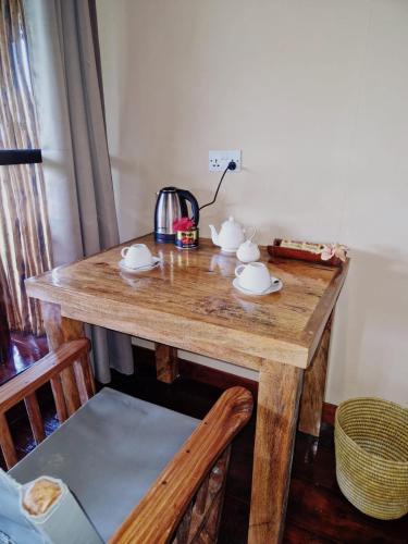 a wooden table with cups and saucers on it at MONKEY MOUNTAIN LODGE in Mtende