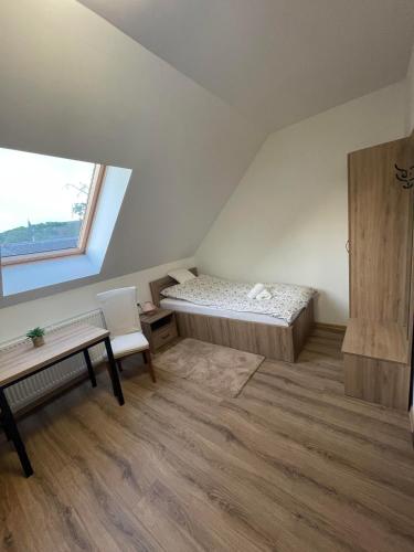 a bedroom with a bed and a desk and a window at Páca-hegyi szálláshely in Erdőhorváti