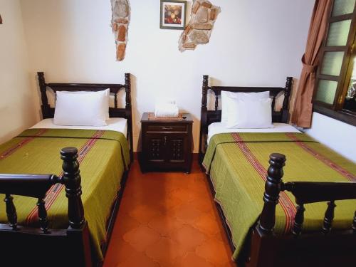 a bedroom with two beds and a table with a night stand at La Quinta Santa Lucia in Antigua Guatemala
