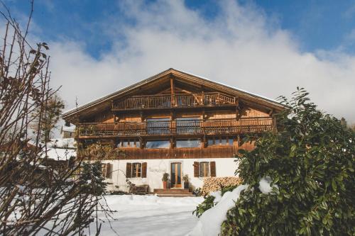 Cette grande maison en bois dispose d'un balcon dans la neige. dans l'établissement Ferme du Ciel, à Samoëns