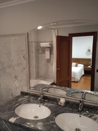 a bathroom with two sinks and a large mirror at Hotel Sablón in Llanes