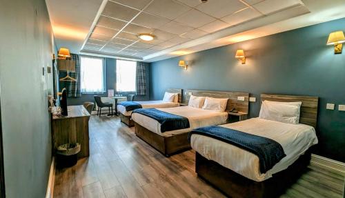 a hotel room with two beds and a desk at Inn On The Coast in Portrush