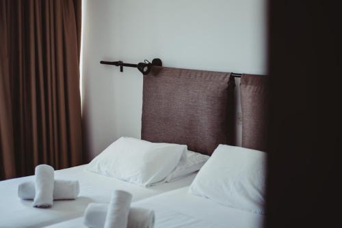 a bed with white pillows and a brown head board at Ovis Hotel Apartments in Ayia Napa