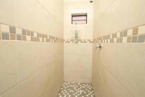 a bathroom with a shower with a tiled floor at Hhusha Hhusha in Malelane