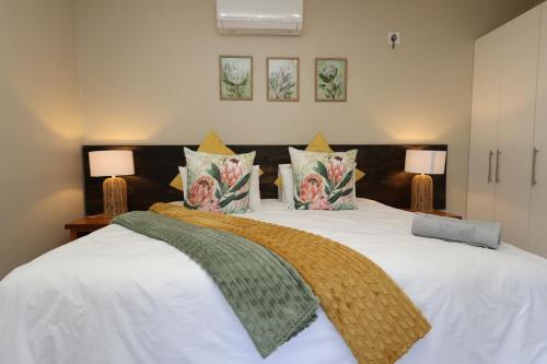 a bedroom with a large white bed with two lamps at Hhusha Hhusha in Malelane