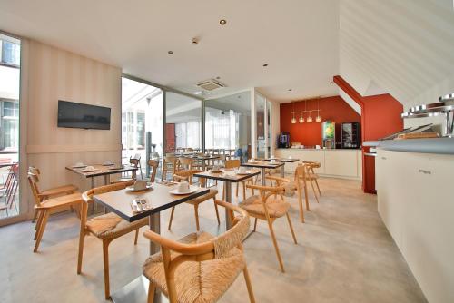 a restaurant with tables and chairs and a kitchen at Aparthotel Adagio Strasbourg Place Kleber in Strasbourg