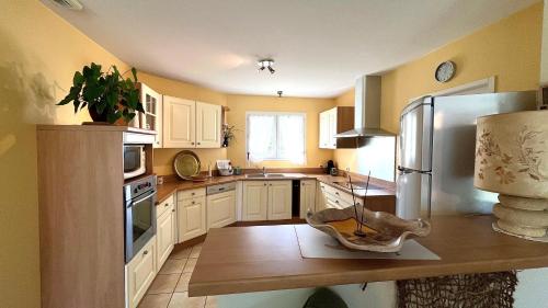 une cuisine avec des armoires blanches et un réfrigérateur en acier inoxydable dans l'établissement VILLA FANTINI - Maison 3 chambres Centre-Ville, à Mimizan