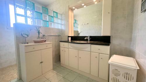 une salle de bain blanche avec un lavabo et un miroir dans l'établissement VILLA FANTINI - Maison 3 chambres Centre-Ville, à Mimizan