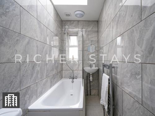 a bathroom with a bath tub and a sink at Large Home for Contractors & Families - Garden & Amenities in London