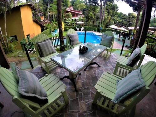 a patio with a table and chairs next to a pool at Pousada Catavento in Arraial d'Ajuda