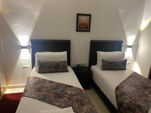 two beds sitting in a room with lights at Hotel Miramar in Tangier