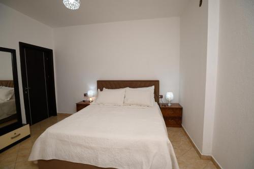 ポグラデツにあるShuli's Apartmentsのベッドルーム(白いシーツ付きのベッド、テレビ付)