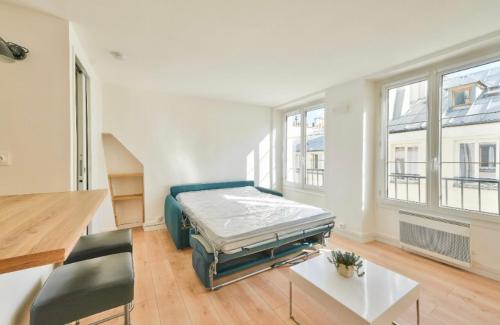 une chambre avec un lit, une table et des fenêtres dans l'établissement Grand Studio Paris 2 EME SENTIER, à Paris