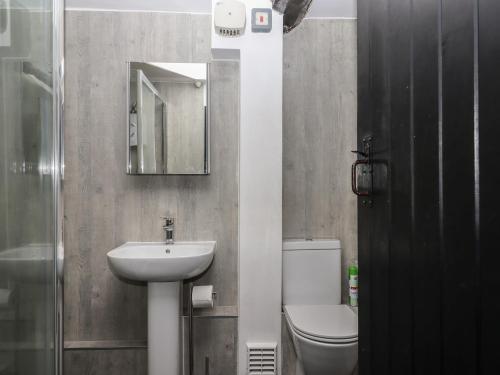 une salle de bain avec un lavabo, des toilettes et un miroir dans l'établissement Warren Cottage, à Sidmouth