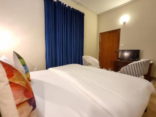 a bedroom with a large white bed with blue curtains at The Life Style Lodges opp Centaurus Mall in Islamabad