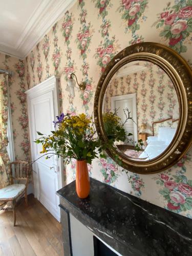 ein Spiegel an der Wand eines Zimmers mit Blumen in der Unterkunft Chambre de Princesse avec Grande Salle de Bain in Blet
