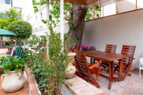 un patio con una mesa de madera, sillas y un árbol en MONDELLO COTTAGE en Mondello