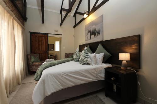 a bedroom with a large bed and a lamp at Hhusha Hhusha in Malelane