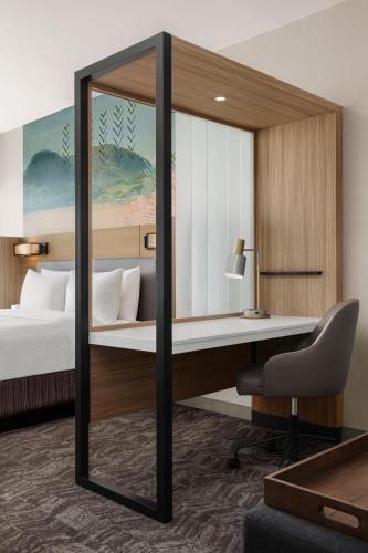 a bedroom with a bed and a desk with a mirror at SpringHill Suites by Marriott Chula Vista Eastlake in Chula Vista