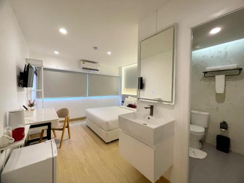 a white bathroom with a bed and a sink at Arawana Express Sukhumvit 22 in Bangkok