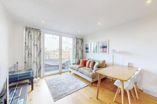 a living room with a couch and a table at Lovely Apartment with Balcony - 3 min to Station in London