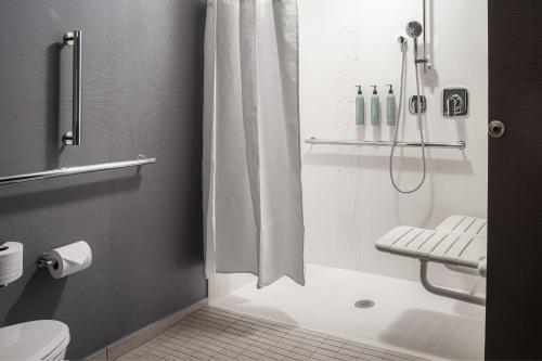 a bathroom with a shower with a toilet and a sink at Courtyard by Marriott Cleveland in Cleveland