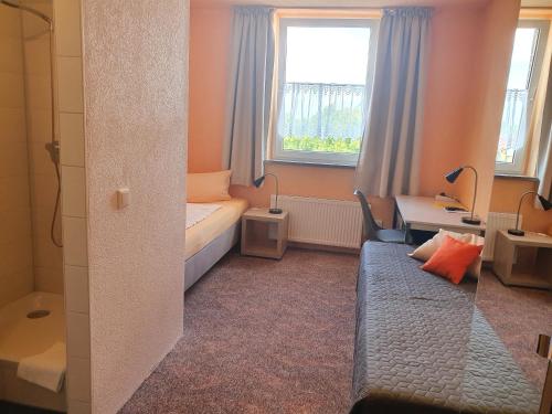 a small room with a bed and a desk and a window at Hotel-Pension Grüne Linde in Delitzsch