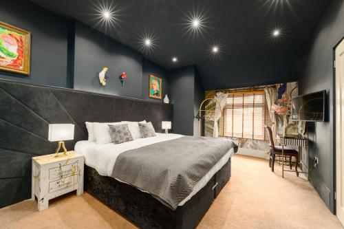 a bedroom with a large bed and blue walls at City Retreat, Spacious 4 Bed House, Games Room, Parking, Hot Tub & BBQ in Cardiff