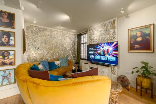 a living room with a yellow couch and a tv at City Retreat, Spacious 4 Bed House, Games Room, Parking, Hot Tub & BBQ in Cardiff