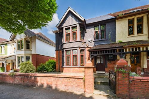 a house with a brick fence in front of it at City Retreat, Spacious 4 Bed House, Games Room, Parking, Hot Tub & BBQ in Cardiff
