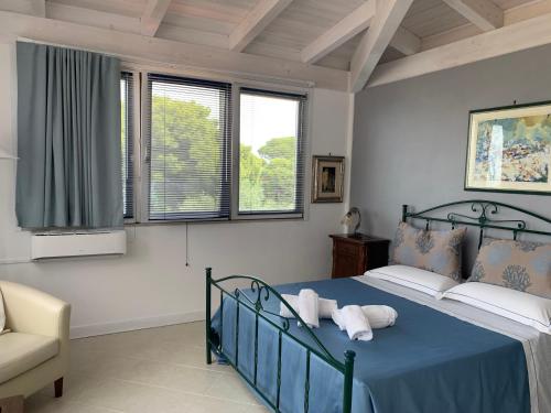 - une chambre avec un lit bleu, une chaise et des fenêtres dans l'établissement Dreaming Penthouse, à Vieste