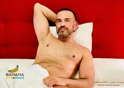 Um homem sem camisa deitado numa cama em Banana Gay House - Only Men em Sevilha