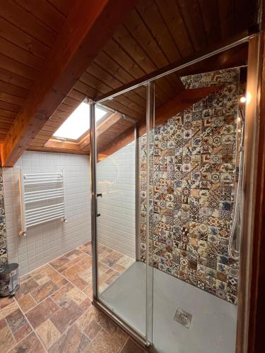 a glass shower in a bathroom with a stone wall at CASA RURAL EL TORREON in Fontiveros
