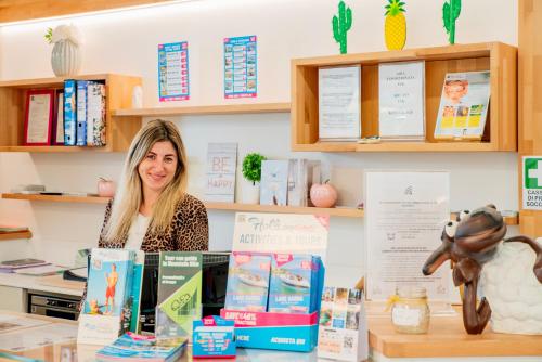 a woman standing behind a counter with books at Residence Molino - Holiday Apartments in Manerba del Garda