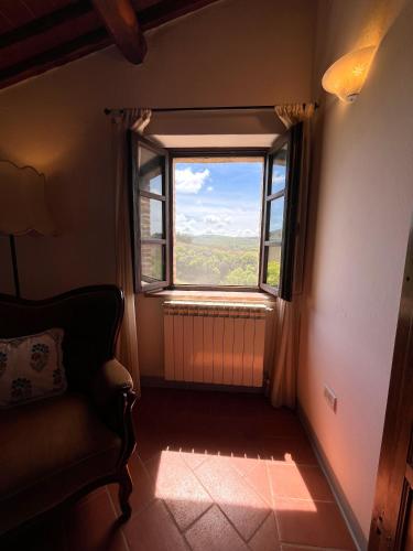 a room with a window with a chair and a view at Podere Sole in Trequanda