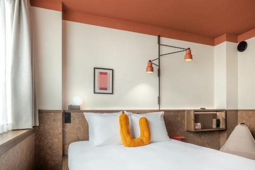 um quarto com uma cama com almofadas brancas em The Usual Brussels em Bruxelas