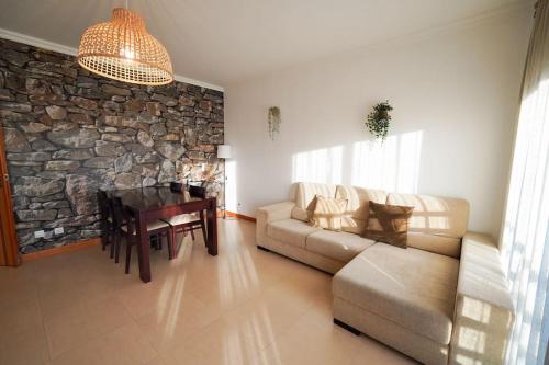 een woonkamer met een bank, een tafel en een stenen muur bij Dream House in Nazaré