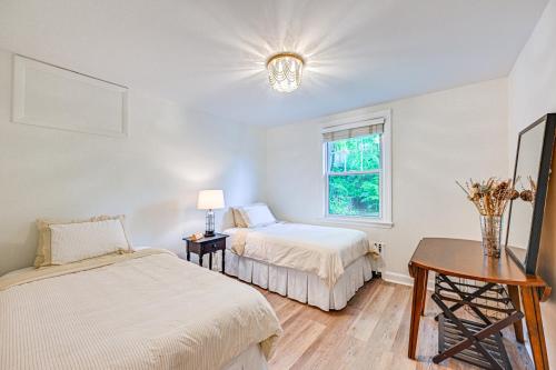 Un dormitorio con dos camas y una mesa y una ventana. en Historic Mamaroneck Guest House - Walk to Harbor!, en Mamaroneck