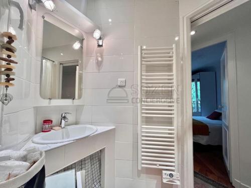 une salle de bain blanche avec un lavabo et un miroir dans l'établissement Le Montmartre Paris 18, à Paris