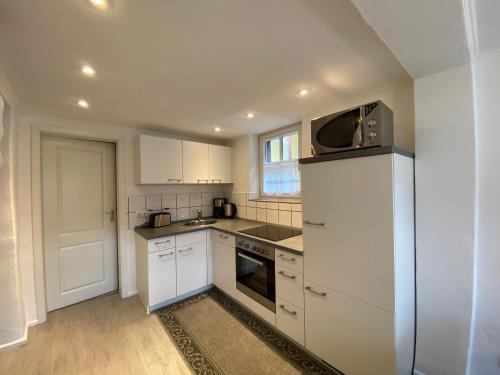 a small kitchen with white cabinets and a microwave at St Lukas Apartments in Oberammergau